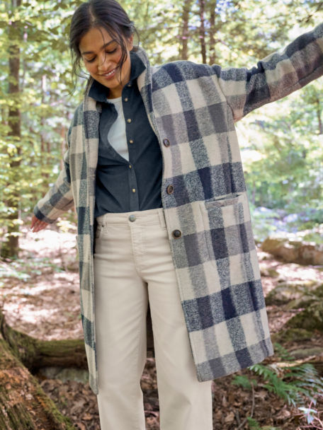 Woman in Saturday Fleece Coat walks along a log in the woods.