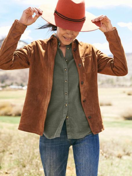 Woman in Garment Dyed Cord Shirt adjusts her Triangle Crown Felt hat in the middle of a grassy field.