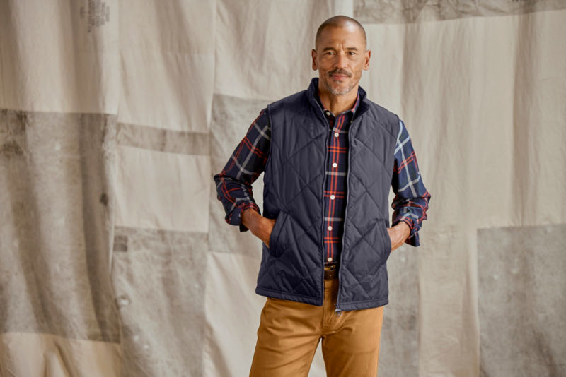 Man wearing navy Barbour vest in studio.