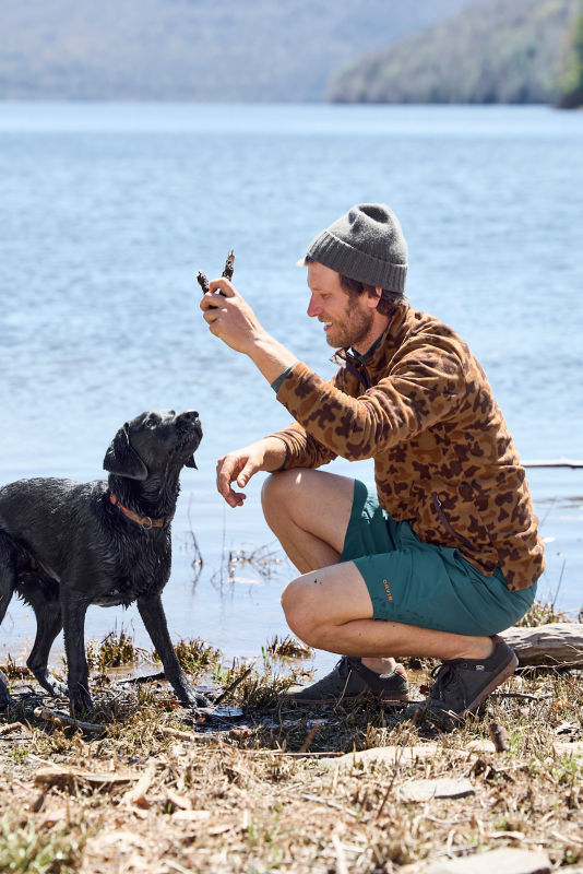 Man plays with dog near pond