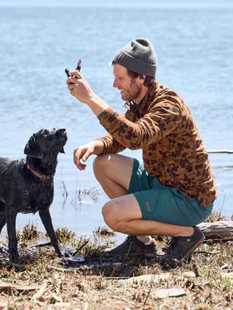 Man plays with dog near pond