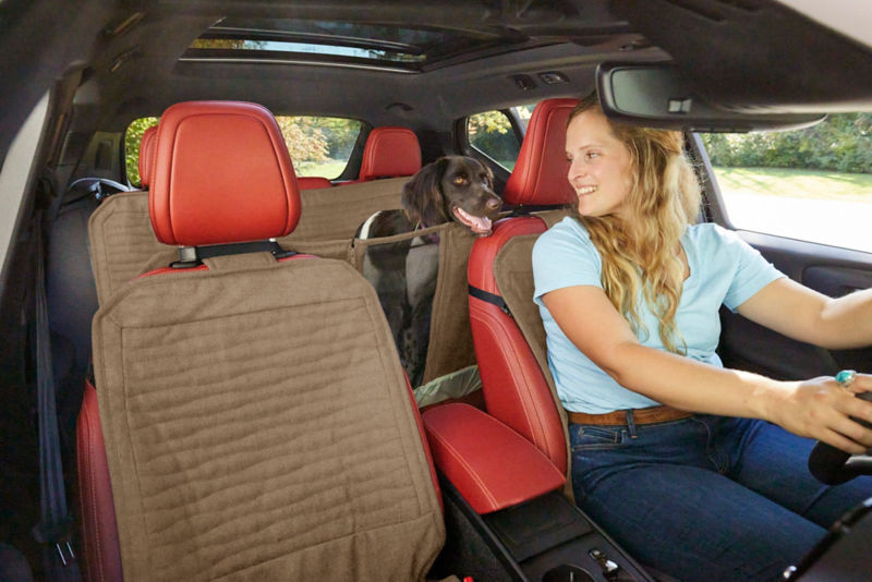 Woman in front seat with her dog on a backseat protector