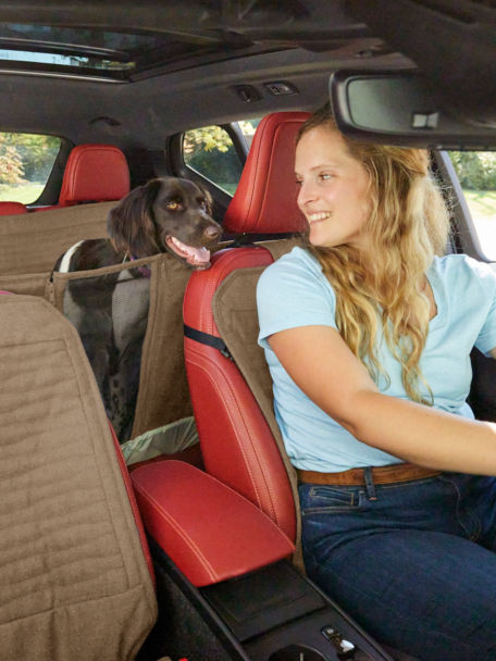 Woman in front seat with her dog on a backseat protector