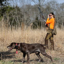 A hunter with a dog on point in a field