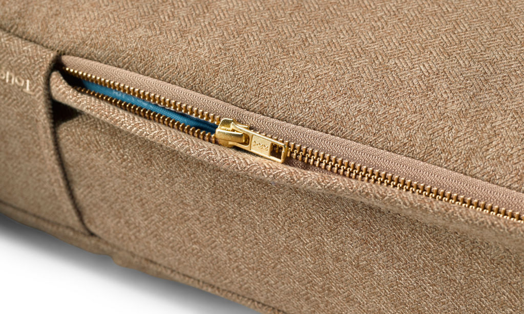 A close-up of a zipper on a camel-tan Toughchew dog bed.
