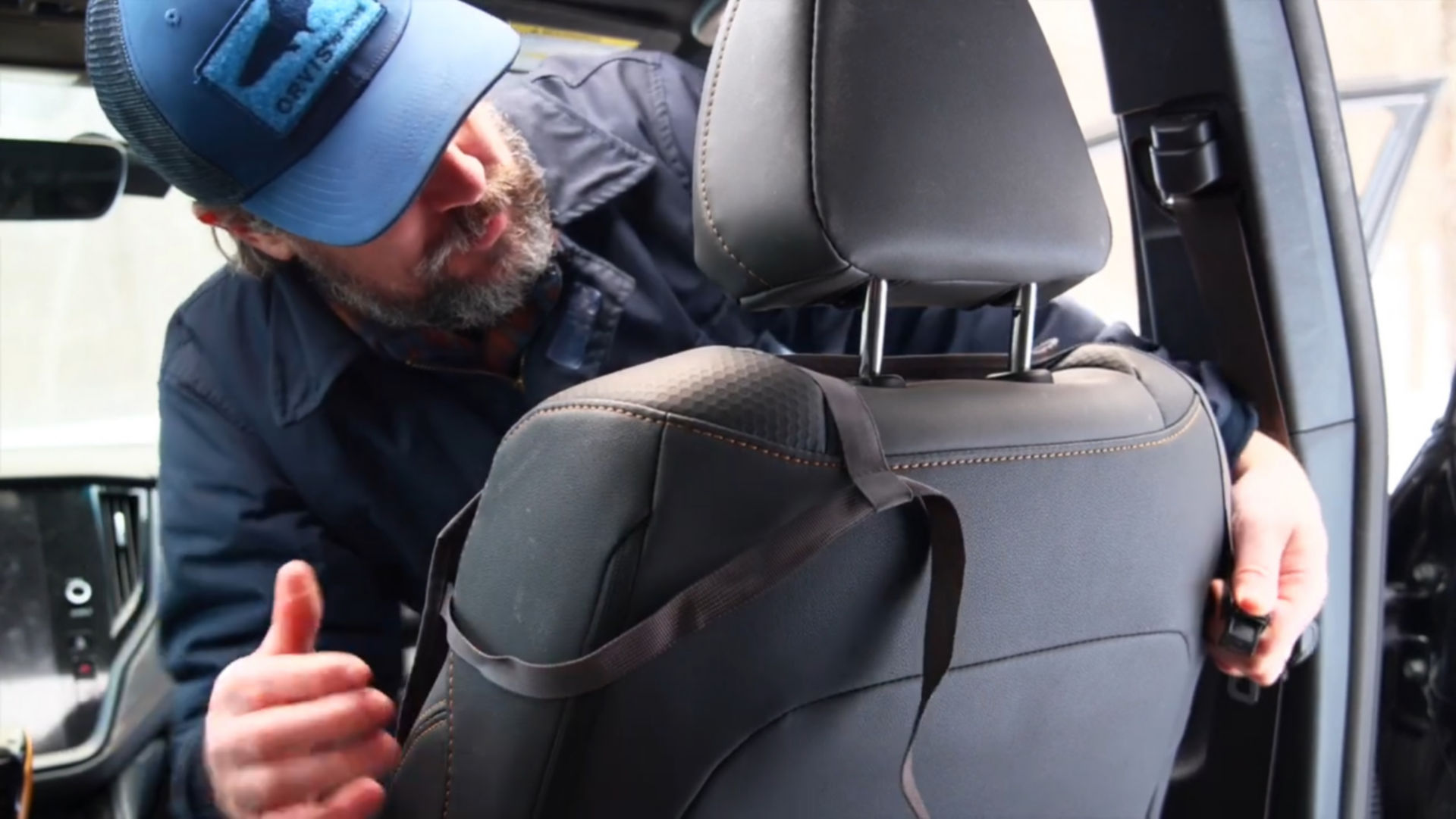 A man installing an Orvis Tough Trail® Grip-Tight® Backseat Protector.