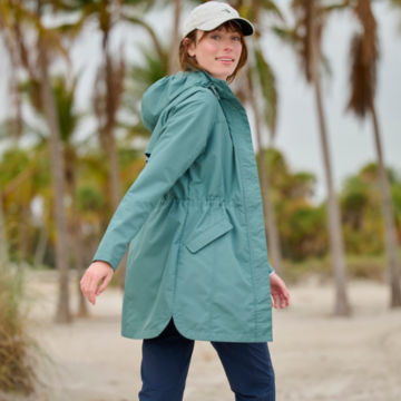 Woman in Pack 'n Go Jacket walks up a path near a beach.