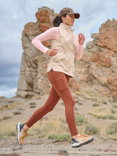Woman in drirelease 1/4 Zip, Zero Limits Fitted Leggings, and Pack N Go Vest goes for a run down a dusty trail.