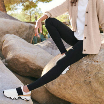 Woman in Journey Ponte Fitted Legging sits on a rock.