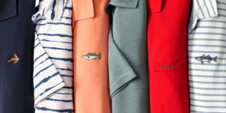 A row of colorful Orvis polos laid out vertically on a hidden surface.
