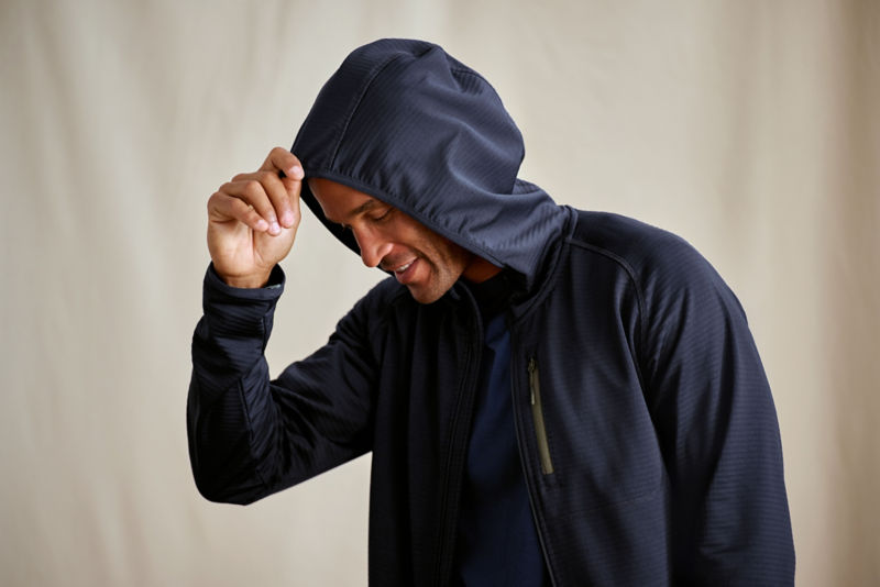 A waist-up view of a model wearing a navy zip-up fleece with hood.