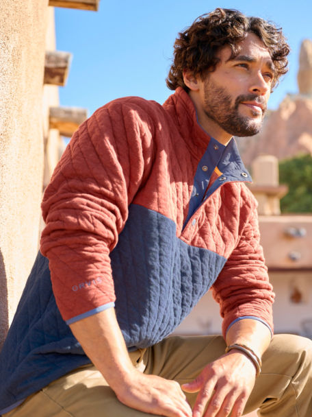 Man wears a colorblock quilted sweatshirt in the desert