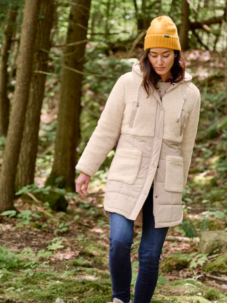 Woman in RT7 Sherpa Mixed Media Coat walks through the woods.