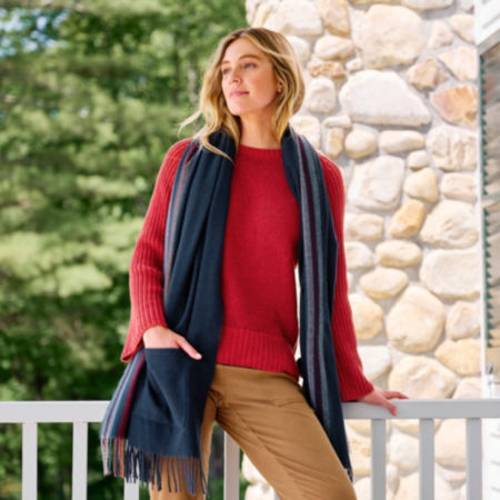 A woman wearing a red crewneck sweater and a navy oversized scarf.