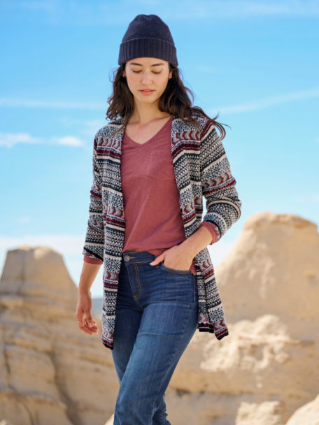 Woman in Stowe Wrap Cardigan walks through a rocky outcropping.