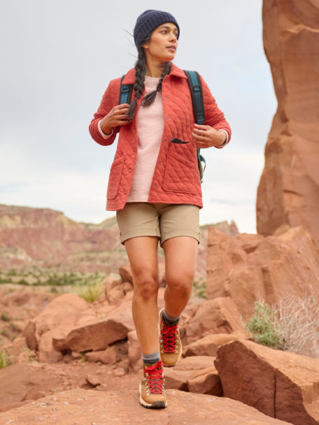 Woman wearing Quilted Shirt Jacket and Jackson Quick Dry Shorts backpacks through a rocky trail in the desert.