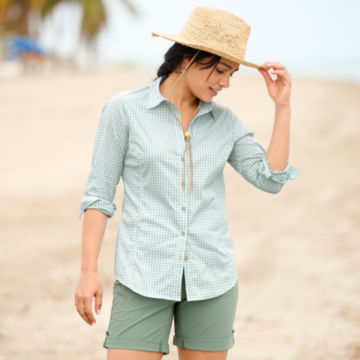 Woman in River Guide Long-Sleeved shirt walks down a beach.