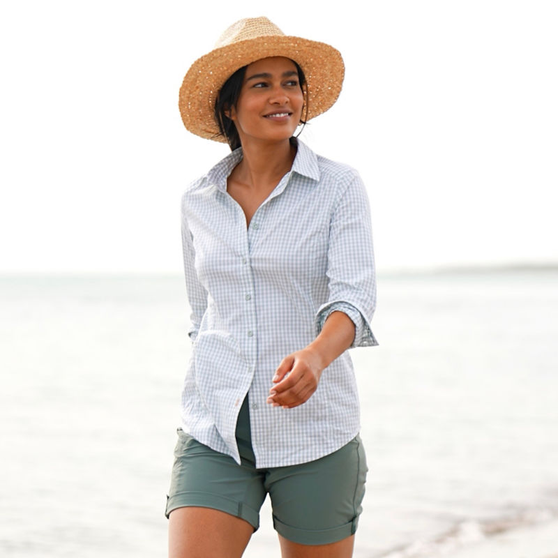 A woman in a River Guide Shirt walks along a beach. image number 7