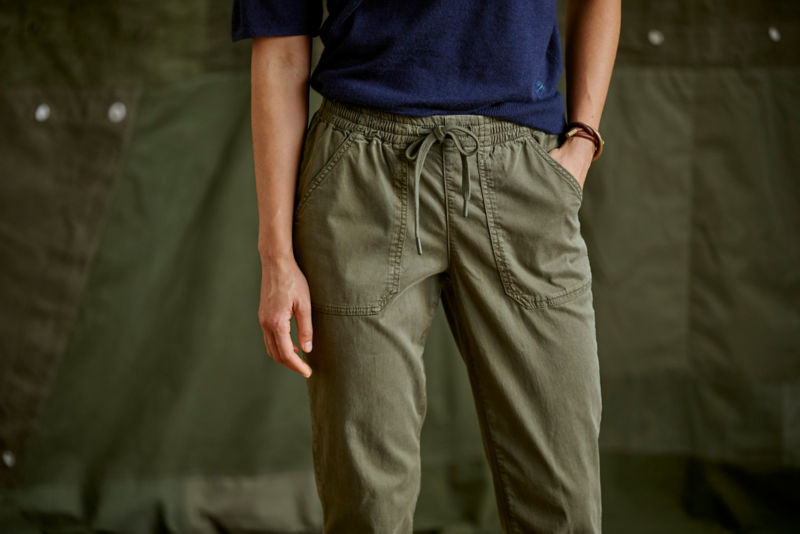 A waist-down view of a model wearing a navy tee tucked into olive drawstring pants.