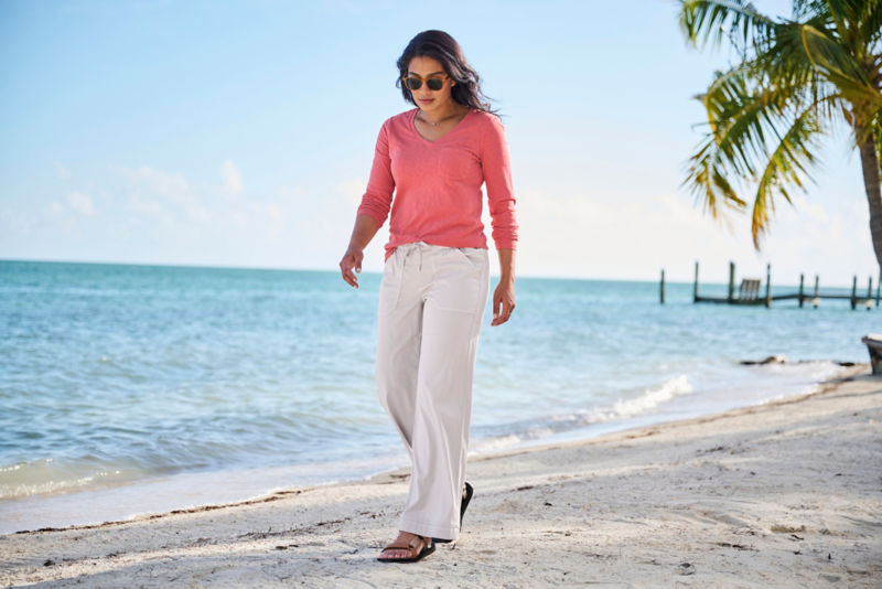 Woman walking the beach in red long sleeve v neck