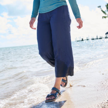 Woman in Wonder Ripstop Wide Leg Cropped pant walks along the beach.