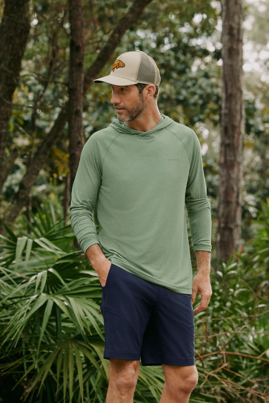 A model wearing a sage green technical hoodie.