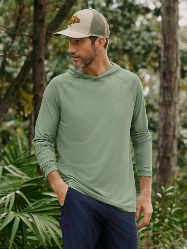A model wearing a sage green long-sleeve tech hoodie.