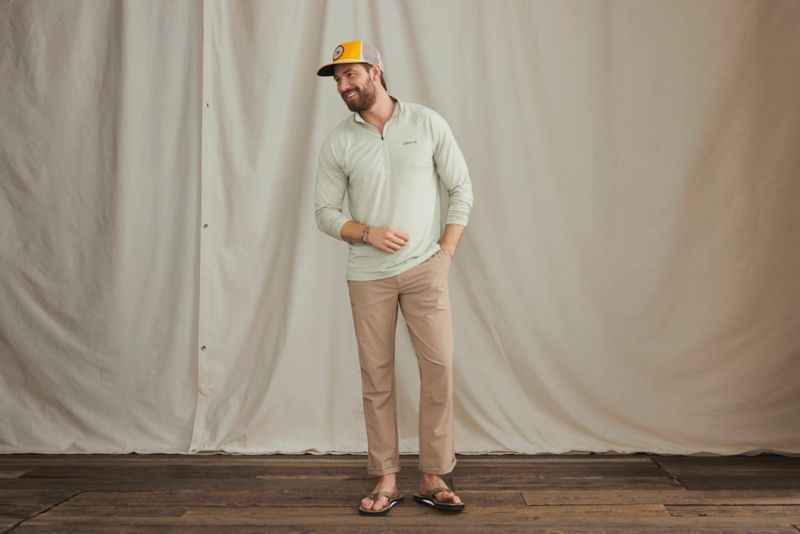A model with his hand in his pocket wearing an Orvis baseball hat and a quarter-zip performance shirt.