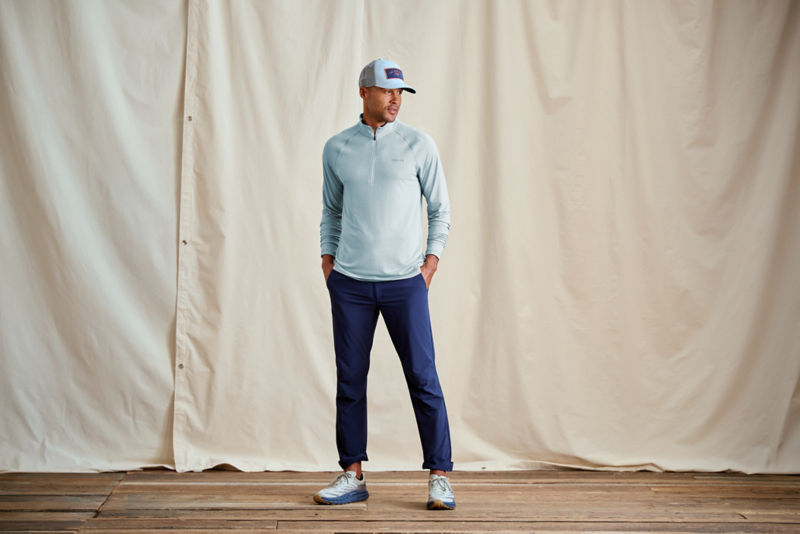 A model wearing an aqua sun protective shirt with navy performance pants.