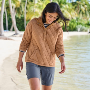 Woman in Lived In Quilted Hoodie walks along the beach.