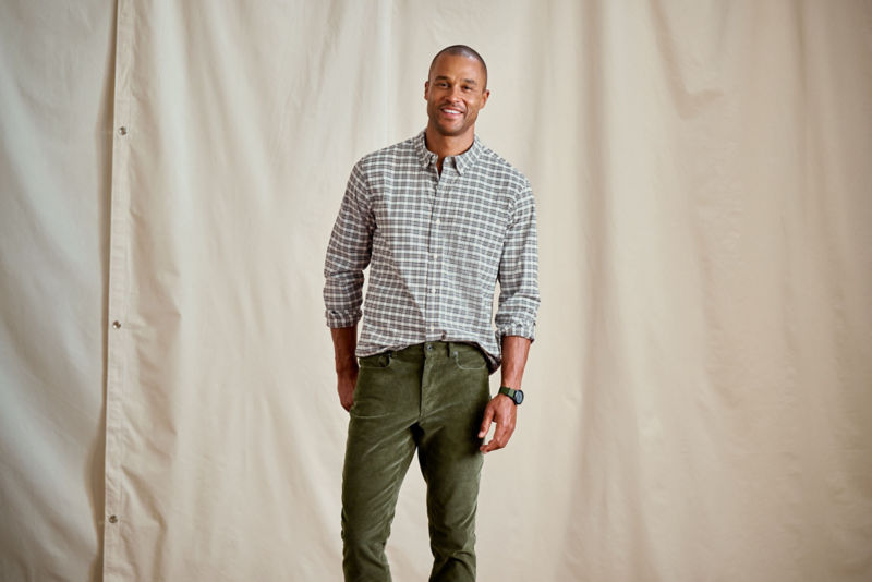 A man wearing a plaid long sleeve shirt with green corduroys.