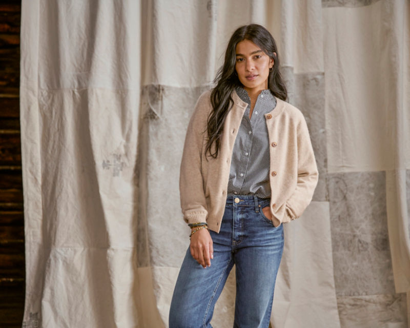 Model wearing cream sweater with plaid shirt and jeans