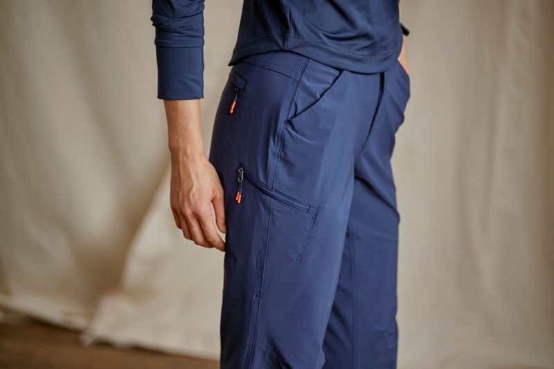 A waist-down view of a model wearing navy performance technical pants with a navy tee.