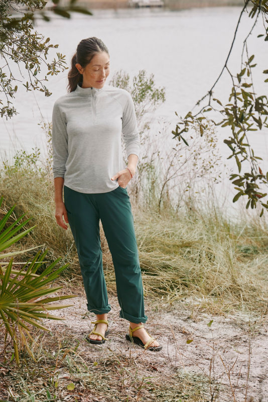 A waist-down view of a model wearing teal mid-rise pants with a gray sun protective shirt.