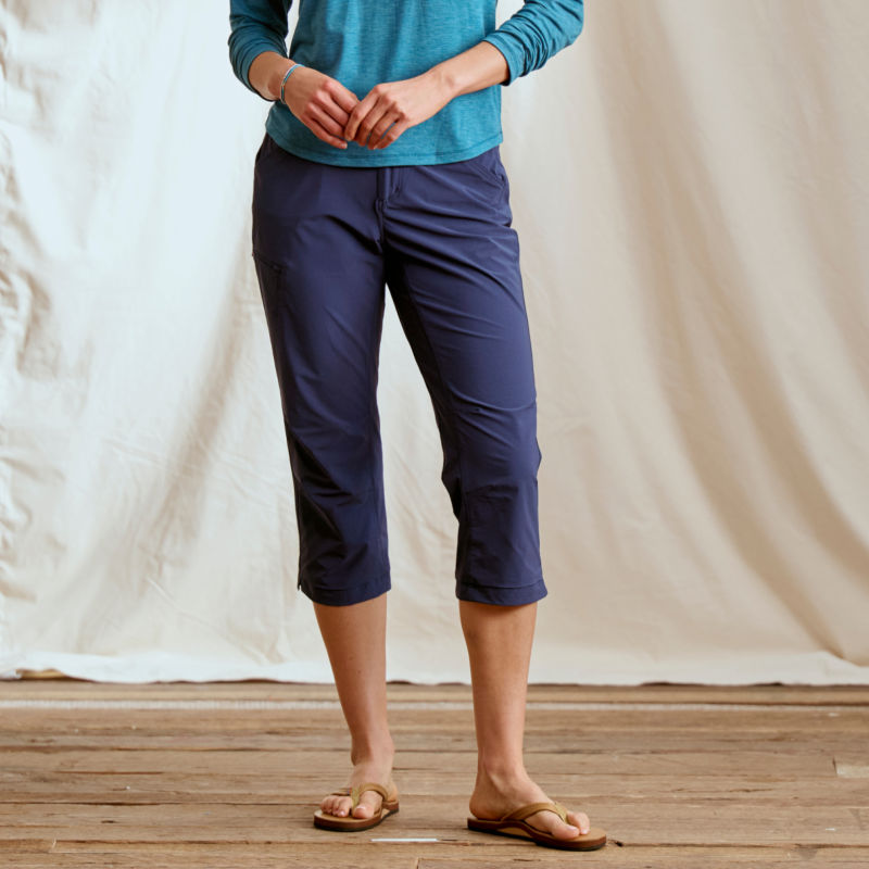 A waist-down view of a model wearing blue pedal pushers with a teal sun protective shirt.