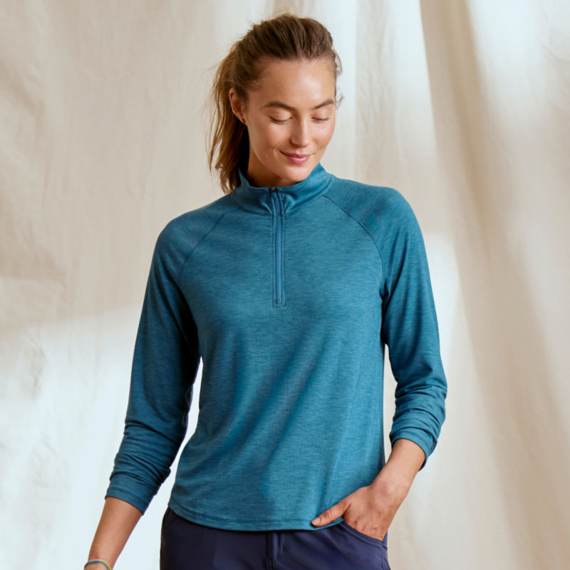 A model wearing a dark teal sun protection quarter-zip.