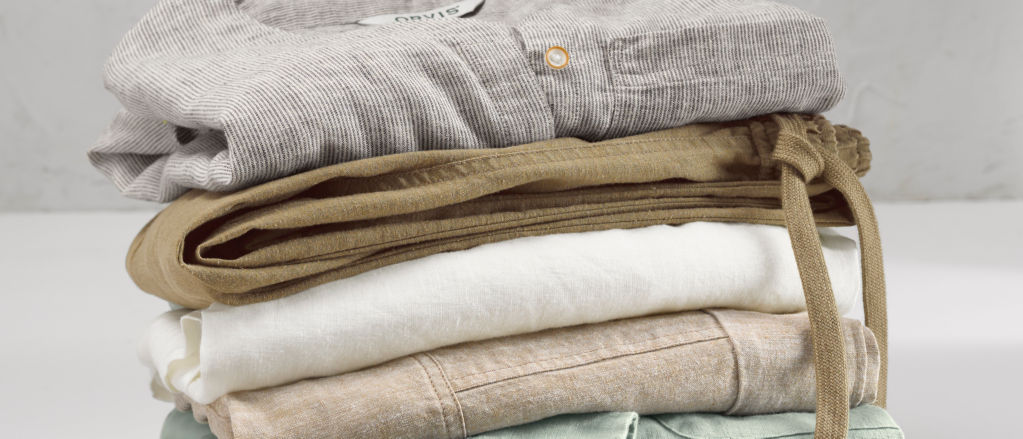 A stack of linen shirts and pants ready to pack for an adventure.
