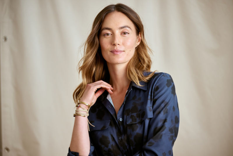 A waist-up view of a model wearing a navy silk button-down shirt with a floral pattern.
