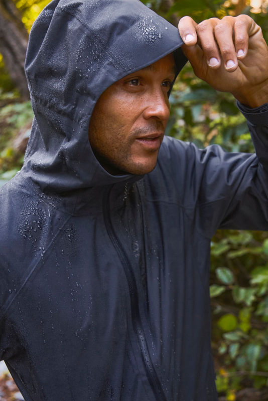 A model in a blue rain jacket dotted with beads of rain.