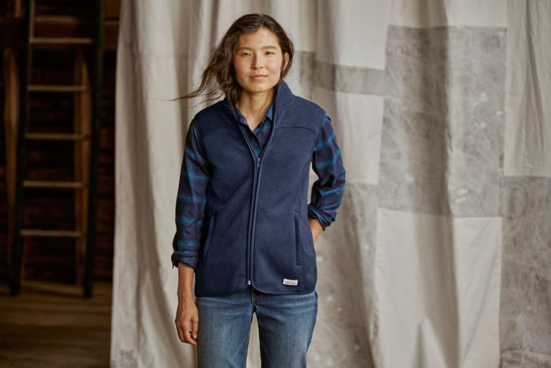 Model wearing navy vest over navy plaid flannel