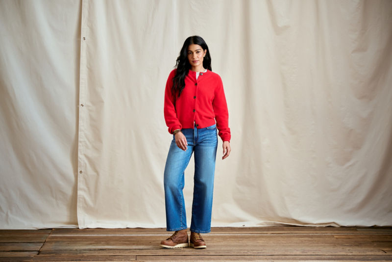 A woman wearing a bright red cardigan over a white tee.