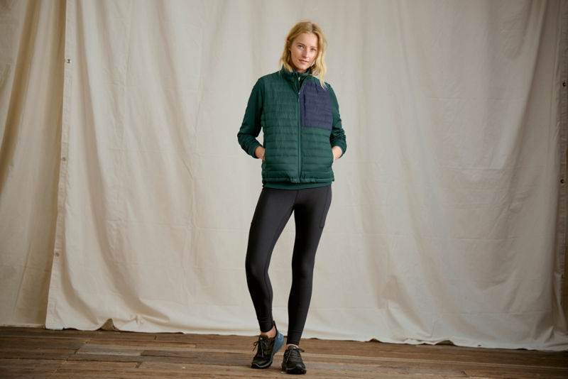 Woman wearing teal quilted vest and leggings in a studio.