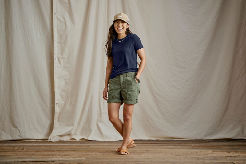 Woman wearing navy tee and green shorts in a studio.