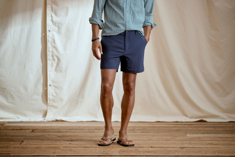Man wearing blue plaid shirt and navy shorts in a studio