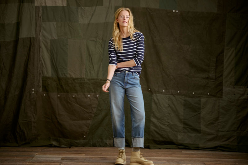 Woman wearing navy and white striped tee and jeans in a studio.