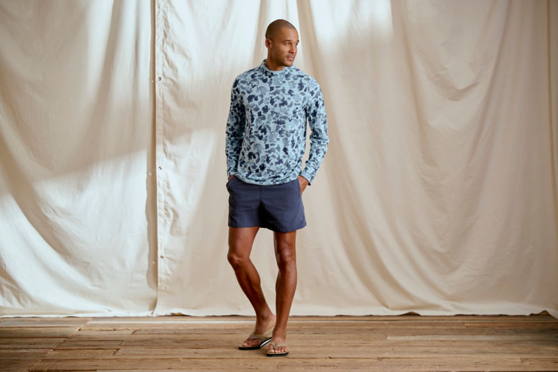 Man wearing blue camo hoodie and navy shorts in a studio.