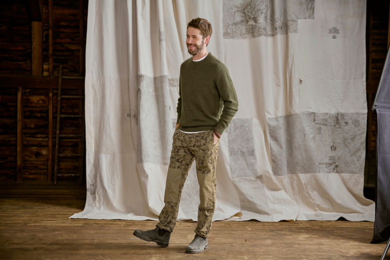 Man wearing green crewneck sweater in studio.