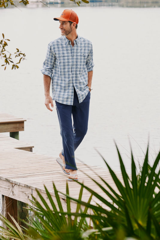 Man wearing blue plaid shirt standing in front of the water.