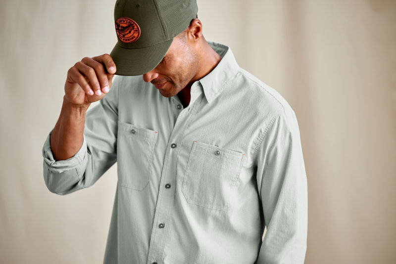 A model wearing a soft green button-down shirt with an olive ball cap.
