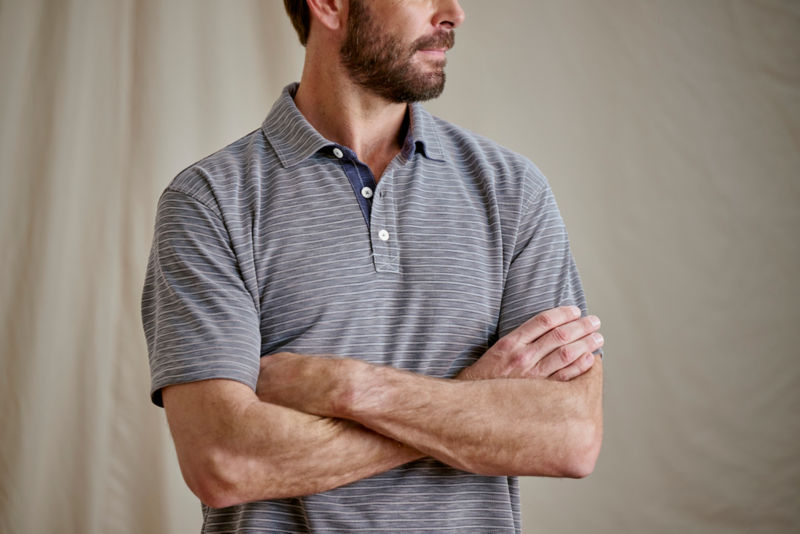 Model wearing striped polo with arms crossed